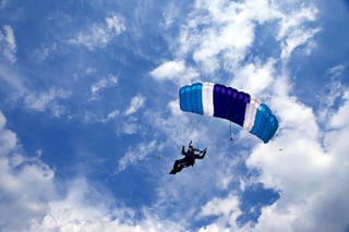 Skydiver gliding under blue sky