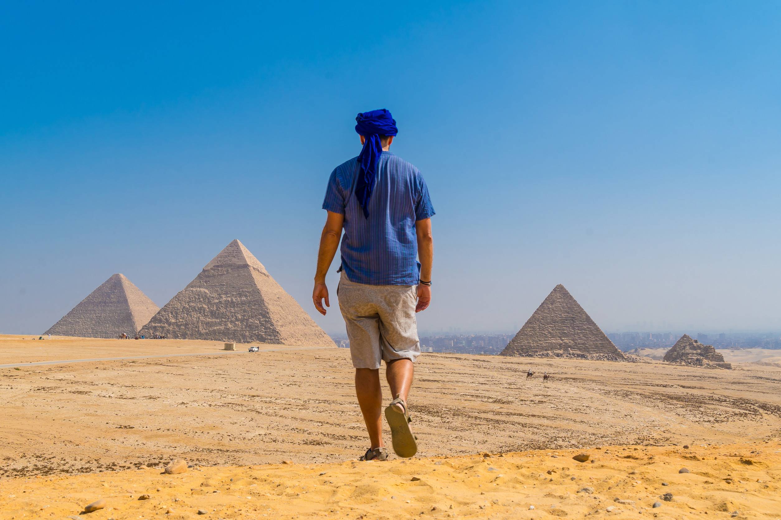 https egypt eta com images a young man in a blue turban walking next to the pyramids of giza the oldest funerary mo