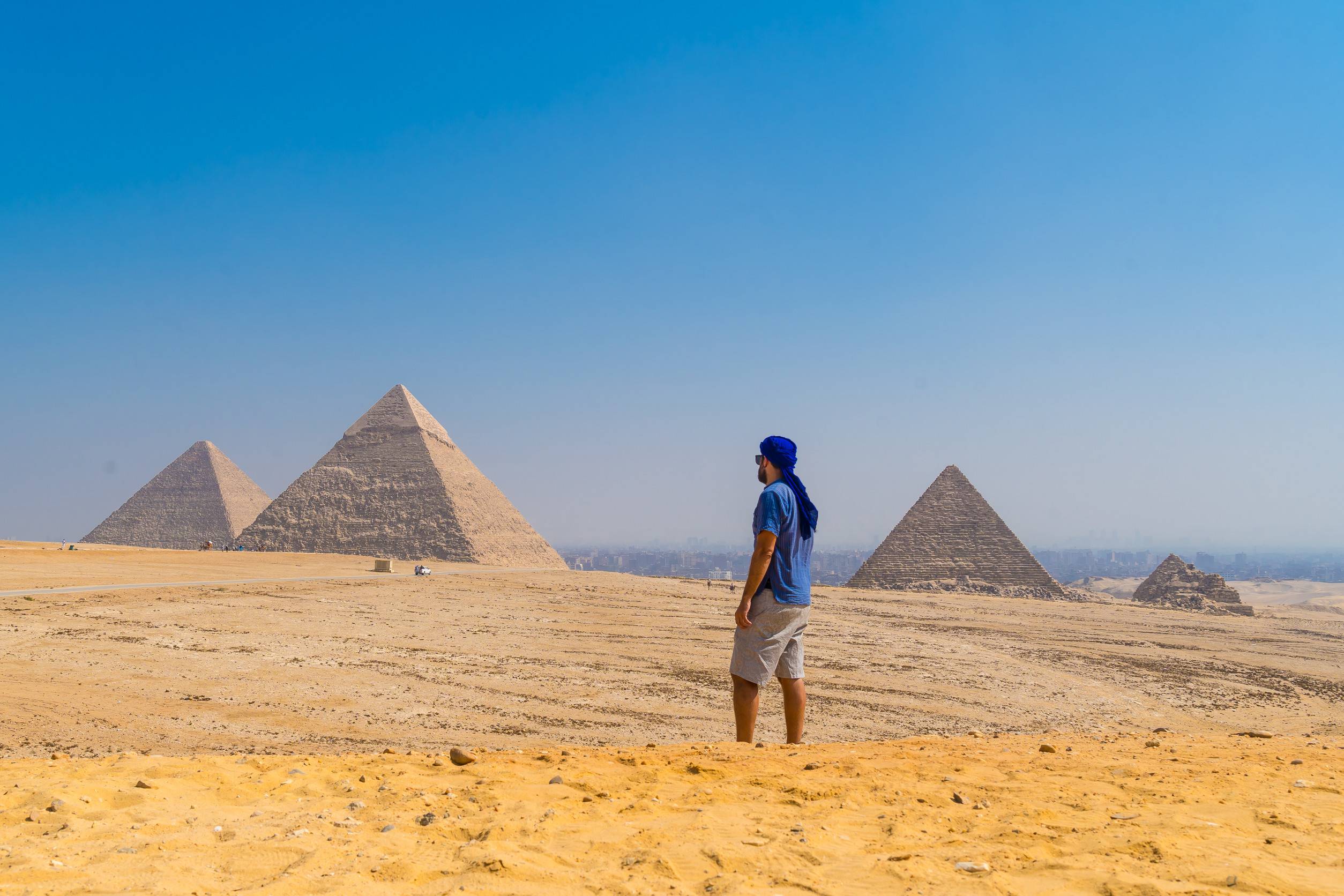 https egypt eta com images a young man in a blue turban walking next to the pyramids of giza the oldest funerary monument