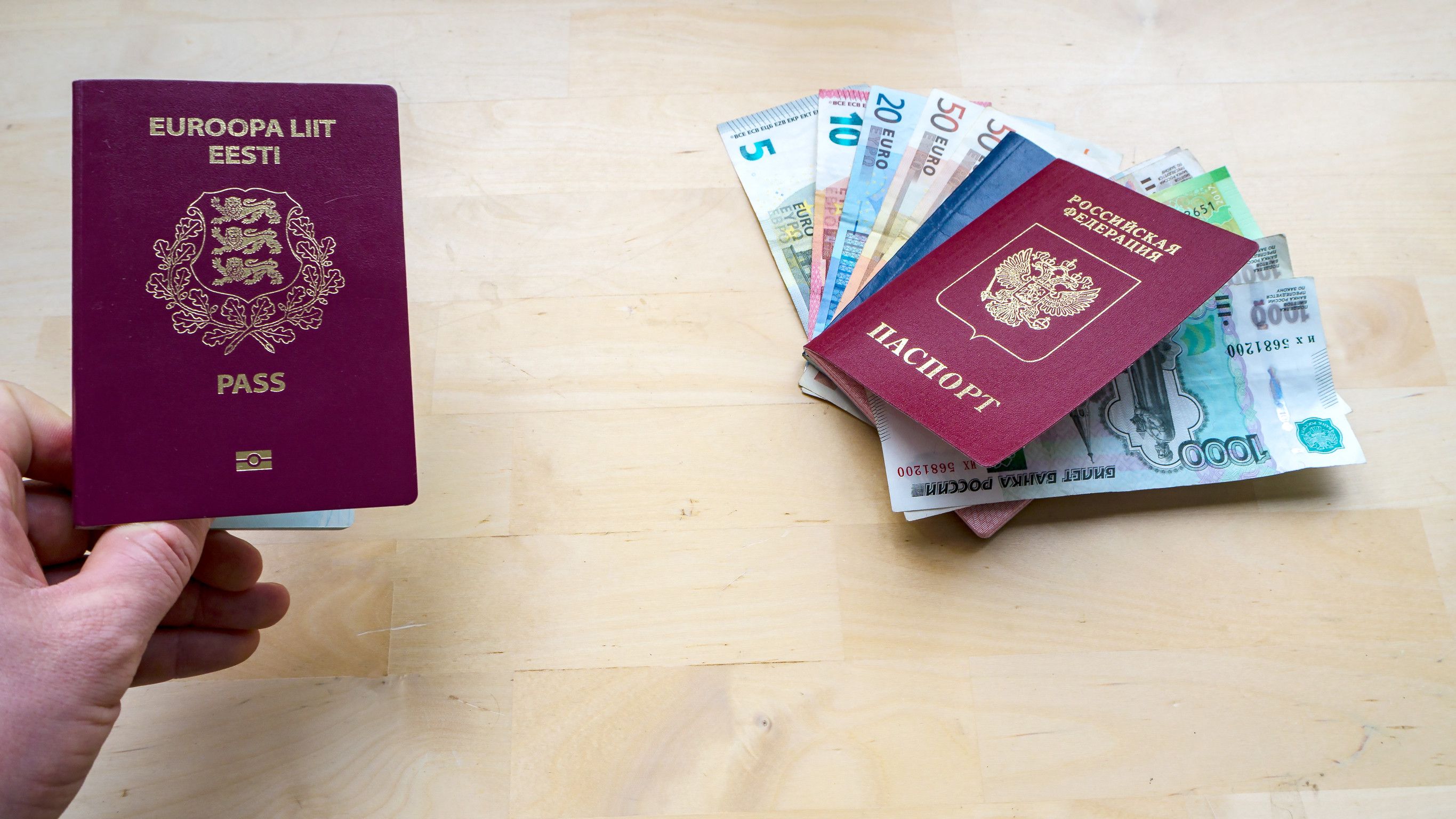 Hand Holding Passport On The Wooden Background Citizenship Of Estonia