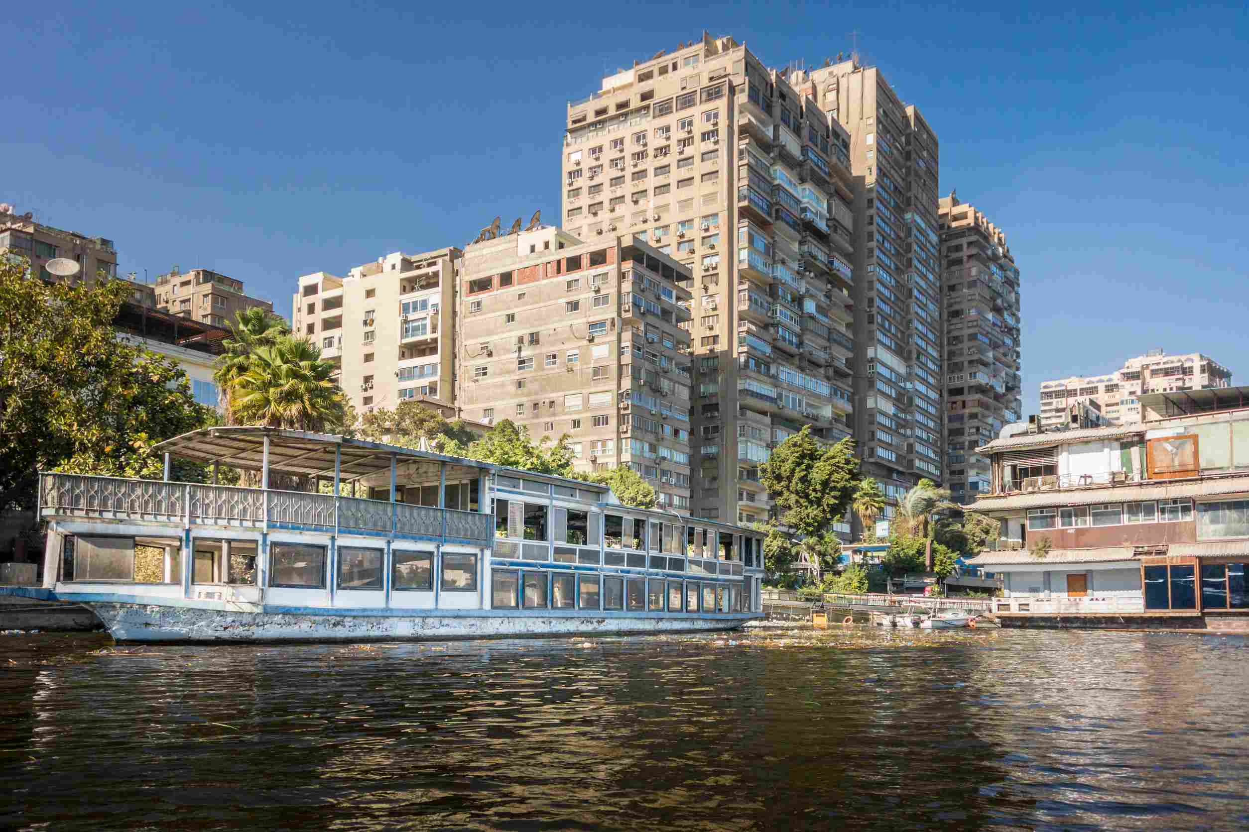 https egypt eta com images tower blocks on the banks of the river nile with a boat in the foreground in the city