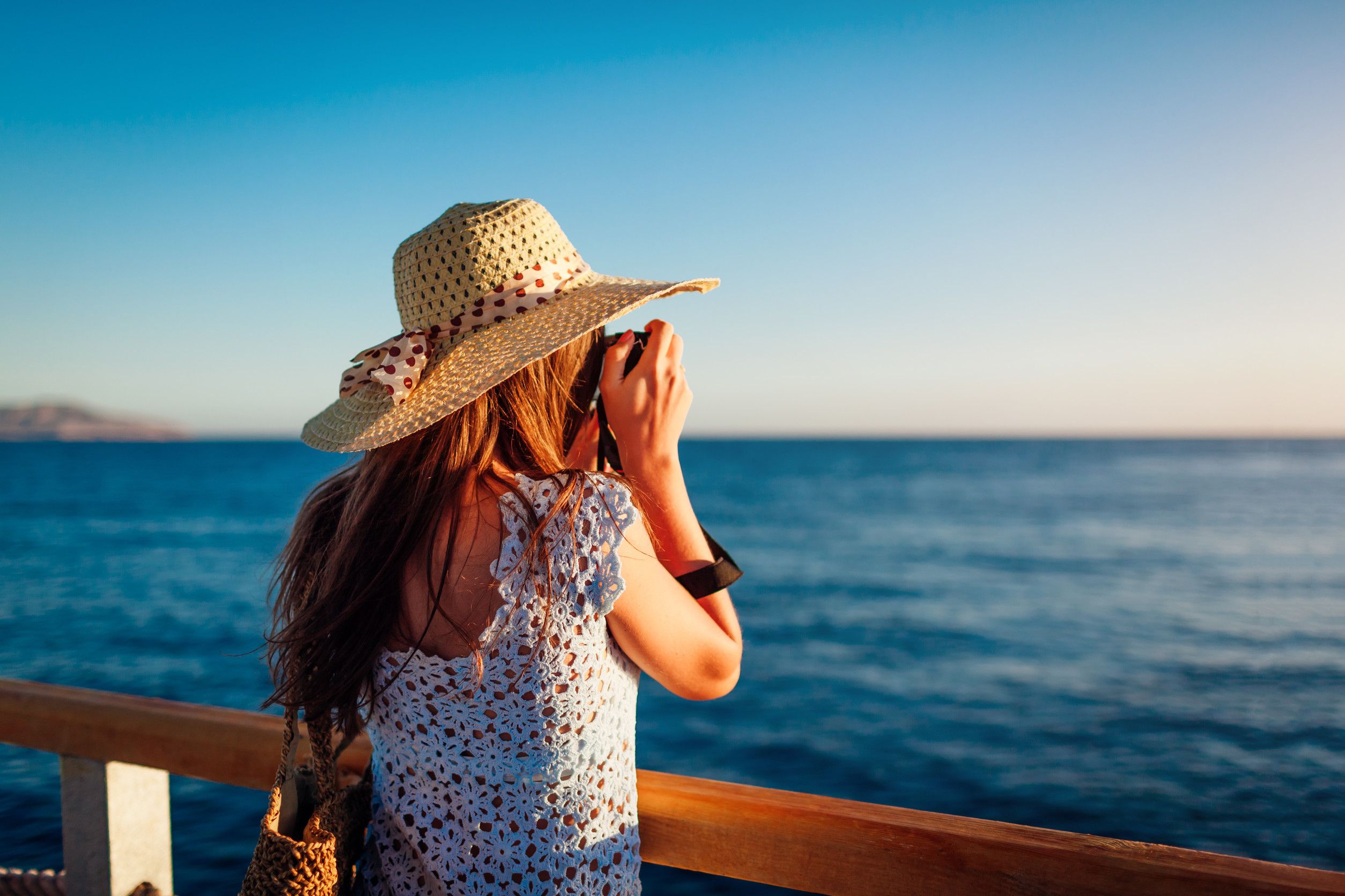 Young Woman Traveler Taking Photos Of Sea Landscape On Pier Using Camera Summer Fashio